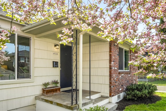 property entrance featuring fence and brick siding