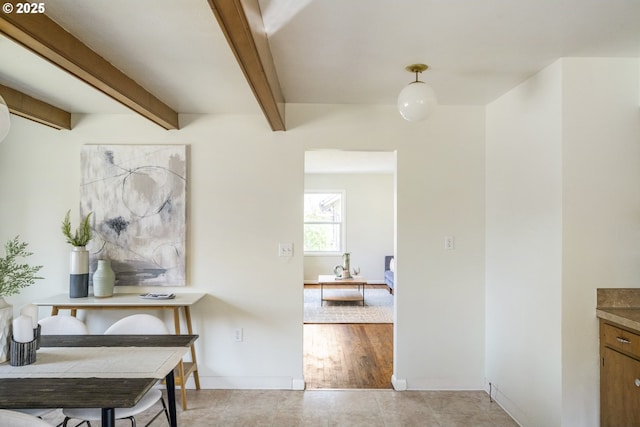 hallway with baseboards and beam ceiling
