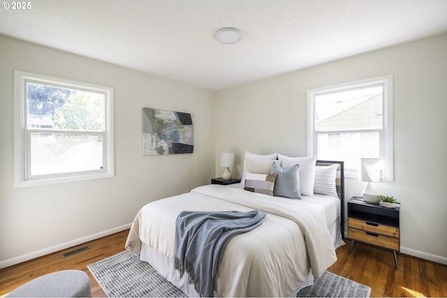 bedroom with baseboards, visible vents, and wood finished floors