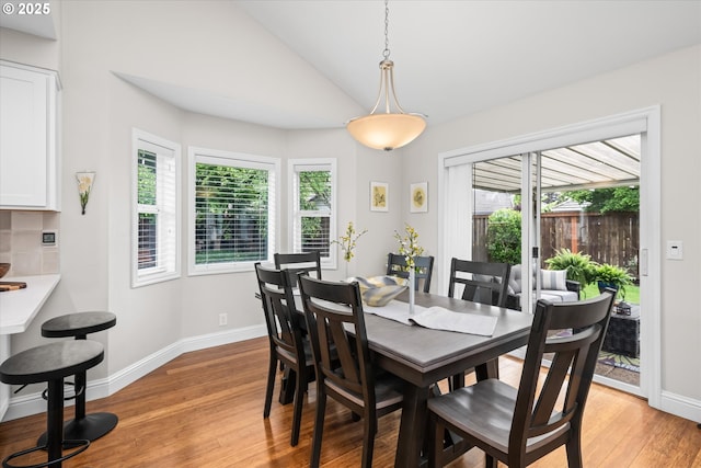 dining room featuring light wood-type flooring, baseboards, and vaulted ceiling