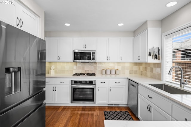 kitchen with stainless steel appliances, a sink, dark wood-type flooring, white cabinets, and recessed lighting