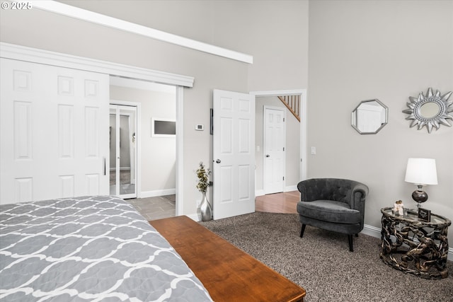 bedroom with a closet, baseboards, carpet flooring, and a high ceiling