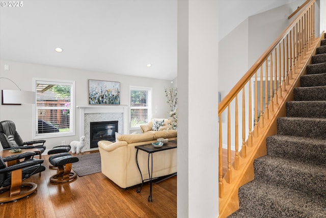 living room with wood-type flooring, stairs, a premium fireplace, and recessed lighting