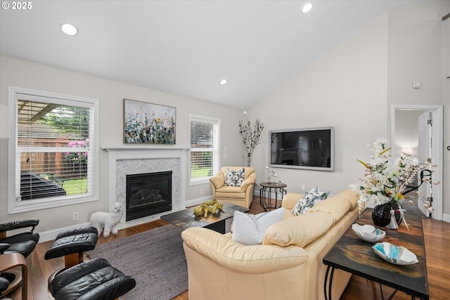 living room with wood finished floors, a premium fireplace, baseboards, recessed lighting, and high vaulted ceiling