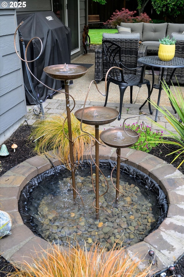 view of patio / terrace featuring a grill and a small pond