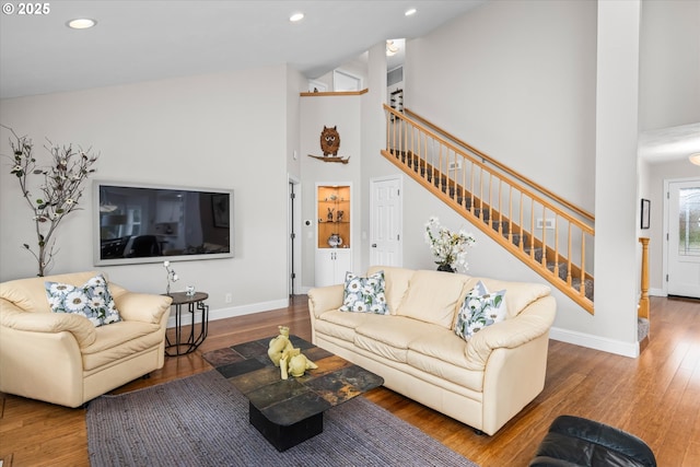 living room featuring stairway, wood finished floors, high vaulted ceiling, baseboards, and recessed lighting