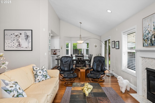 living room with lofted ceiling, a high end fireplace, wood finished floors, recessed lighting, and baseboards