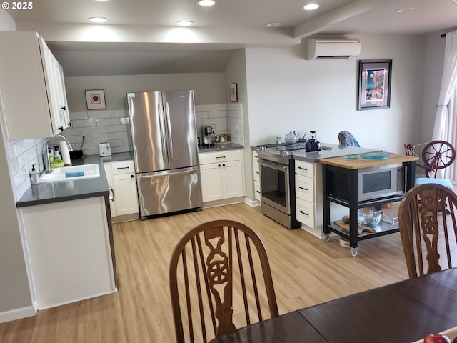 23538 NW Saint Helens Rd Unit S5, Portland, OR 97231 - kitchen featuring appliances with stainless steel finishes, a sink, a wall mounted air conditioner, dark countertops, and light wood-type flooring