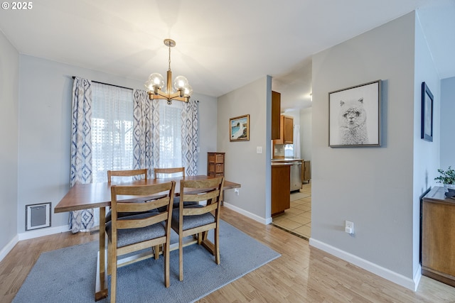 dining room featuring baseboards, light wood-style flooring, and an inviting chandelier