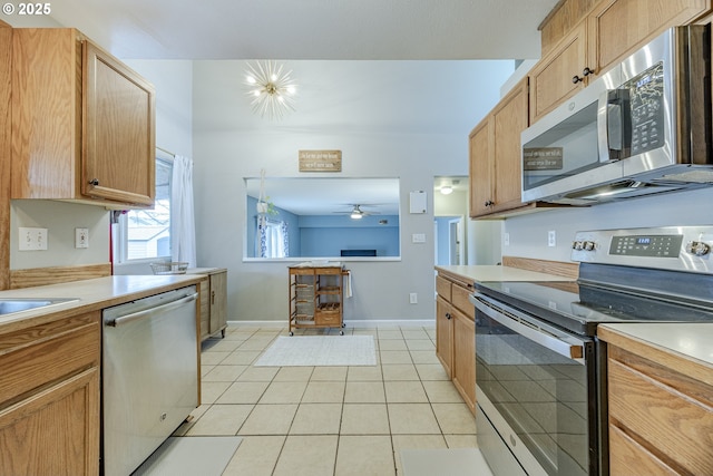 kitchen featuring light tile patterned floors, light countertops, appliances with stainless steel finishes, ceiling fan, and baseboards