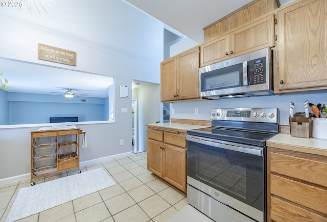 kitchen featuring light tile patterned floors, stainless steel appliances, a ceiling fan, baseboards, and light countertops