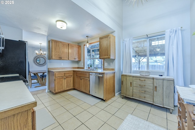 kitchen with decorative light fixtures, light tile patterned floors, light countertops, appliances with stainless steel finishes, and a sink