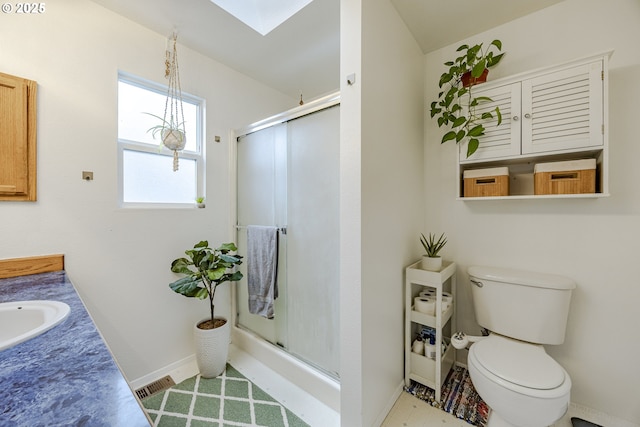 bathroom featuring toilet, a stall shower, a skylight, and visible vents