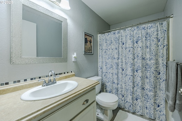 bathroom featuring a textured wall, curtained shower, vanity, and toilet