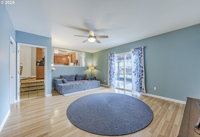 living room with a ceiling fan, baseboards, and light wood finished floors