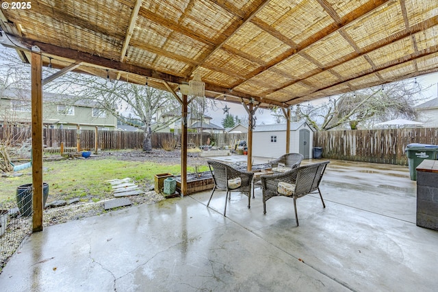 view of patio with a storage shed, a fenced backyard, outdoor dining area, and an outdoor structure