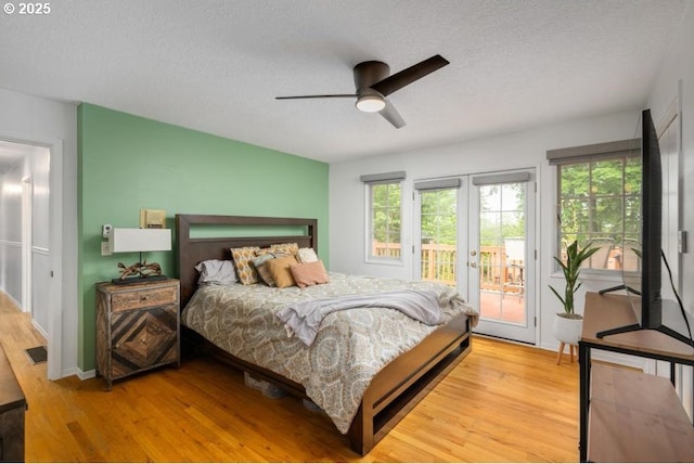 bedroom with a textured ceiling, access to outside, multiple windows, light wood finished floors, and a ceiling fan