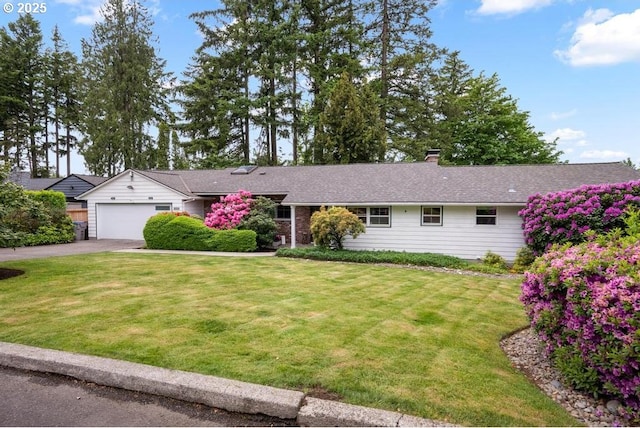 ranch-style house featuring asphalt driveway, a front yard, an attached garage, and a chimney