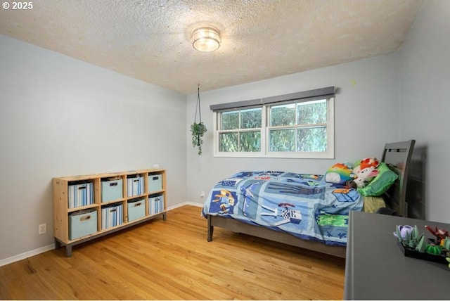 bedroom featuring wood finished floors, a textured ceiling, and baseboards