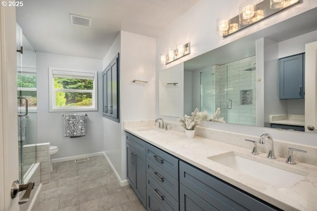 bathroom with a shower stall, toilet, baseboards, and double vanity
