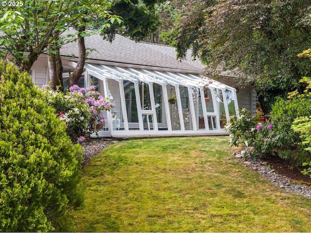 back of property featuring a sunroom, a shingled roof, and a yard