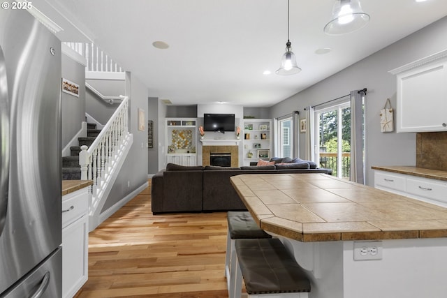 14818 NE 23rd Ave, Vancouver, WA 98686 - kitchen featuring freestanding refrigerator, light wood-style flooring, a glass covered fireplace, white cabinets, and decorative light fixtures