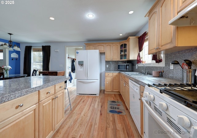 kitchen with under cabinet range hood, light brown cabinets, white appliances, and a sink