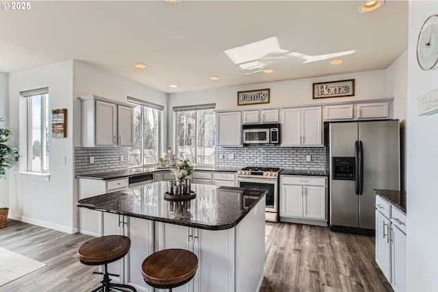12998 SW Kostel Ln, Portland, OR 97224 - kitchen featuring appliances with stainless steel finishes, tasteful backsplash, light wood-style floors, a breakfast bar area, and recessed lighting