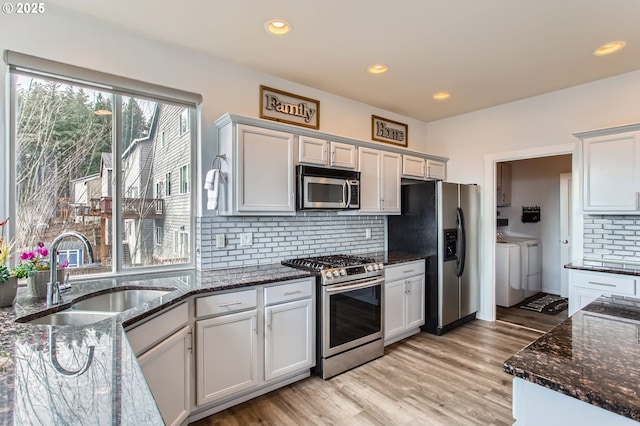 12998 SW Kostel Ln, Portland, OR 97224 - kitchen featuring appliances with stainless steel finishes, washing machine and clothes dryer, a sink, decorative backsplash, and recessed lighting