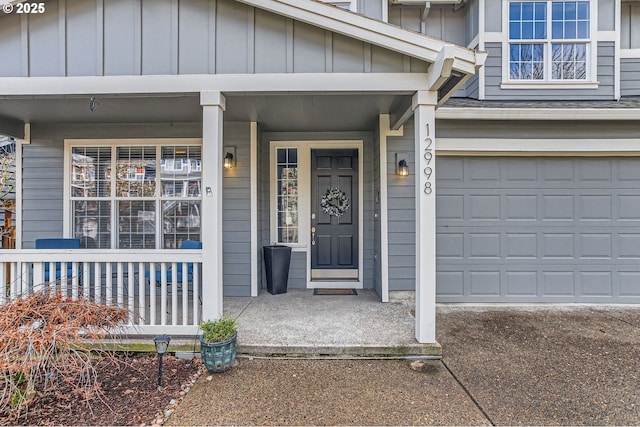 property entrance with an attached garage, covered porch, and board and batten siding