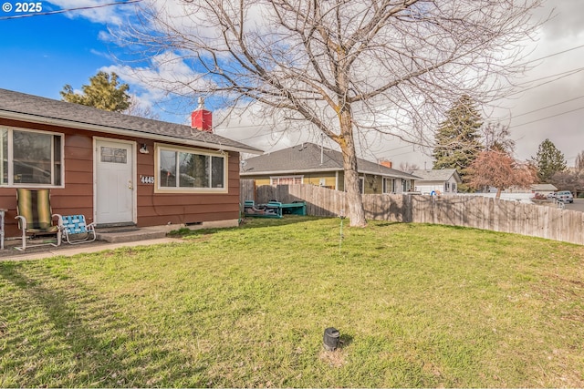 rear view of house featuring crawl space, a chimney, a yard, and fence