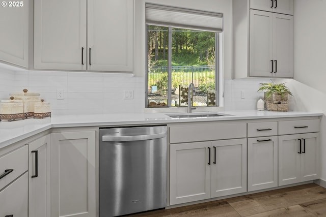 bar featuring wood finished floors, decorative backsplash, a sink, and dishwasher