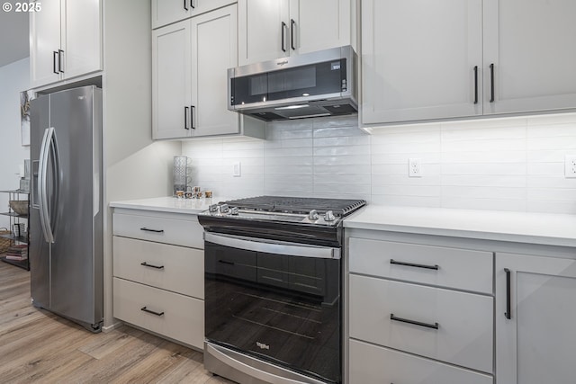 kitchen featuring light wood-style floors, light countertops, appliances with stainless steel finishes, and tasteful backsplash