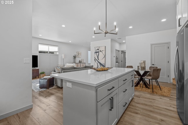 kitchen featuring freestanding refrigerator, light countertops, a kitchen island, and light wood-style floors