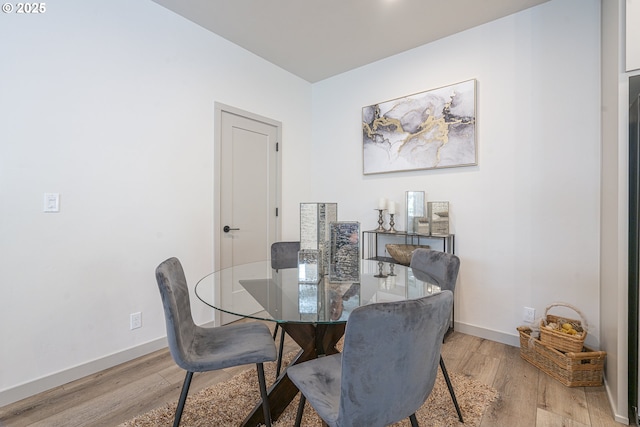 dining area with baseboards and light wood-style flooring