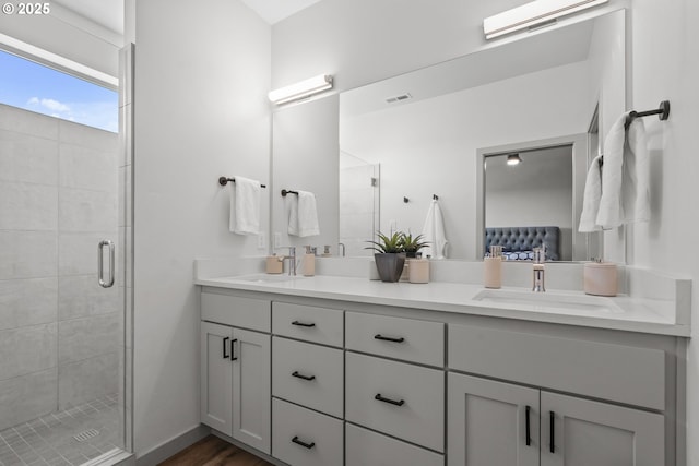 full bath with connected bathroom, double vanity, a sink, and a stall shower