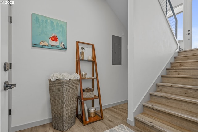 stairway featuring baseboards, vaulted ceiling, wood finished floors, and electric panel