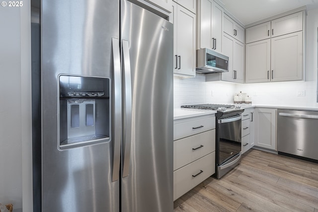 kitchen featuring light countertops, stainless steel appliances, tasteful backsplash, and light wood-style floors