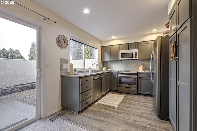 kitchen with a sink, gray cabinets, stainless steel appliances, and light countertops