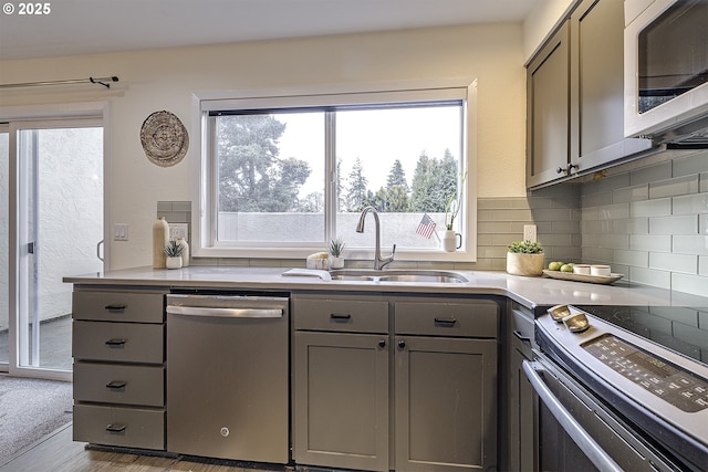 kitchen featuring light countertops, appliances with stainless steel finishes, gray cabinets, and a sink