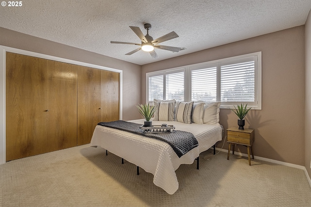 bedroom with baseboards, a ceiling fan, a textured ceiling, carpet floors, and a closet