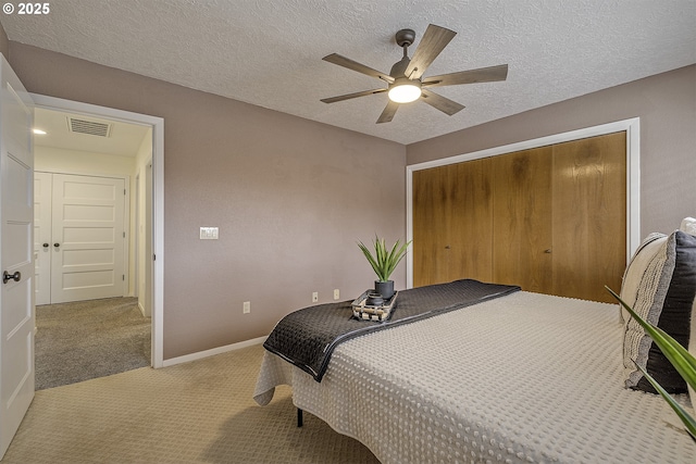 bedroom with a textured ceiling, carpet floors, visible vents, baseboards, and a closet