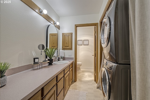 bathroom with stacked washer and clothes dryer, vanity, and toilet