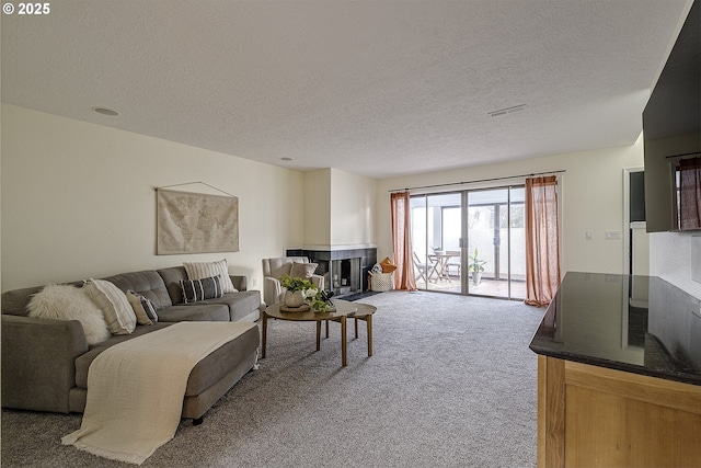 carpeted living room featuring visible vents, a textured ceiling, and a multi sided fireplace