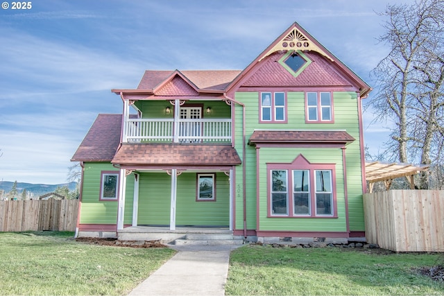 victorian home with a balcony, a front lawn, and a porch