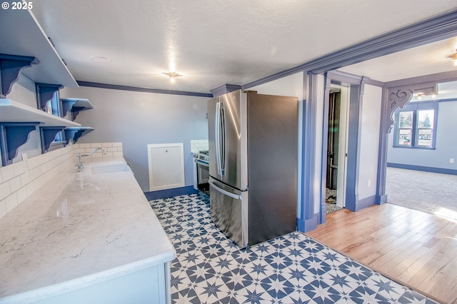 kitchen featuring crown molding, appliances with stainless steel finishes, sink, light stone countertops, and a textured ceiling