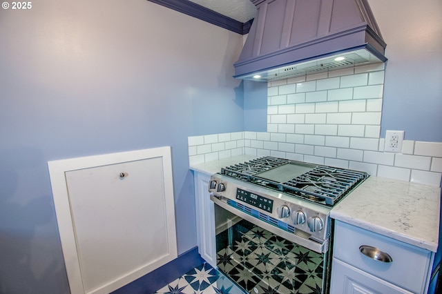 kitchen featuring premium range hood, decorative backsplash, gas range, ornamental molding, and light stone counters