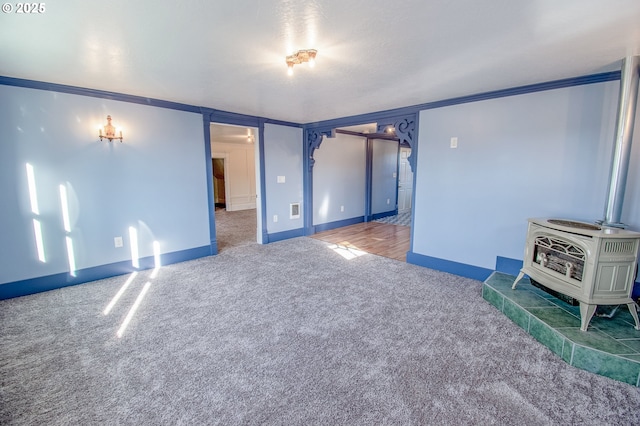 interior space with carpet floors, a wood stove, and crown molding