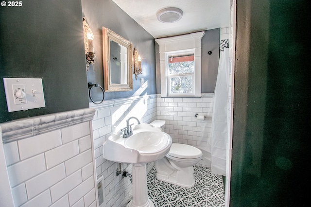 bathroom with tile patterned floors, sink, tile walls, toilet, and walk in shower