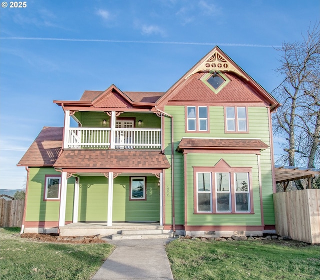 victorian home with a balcony, a front lawn, and a porch